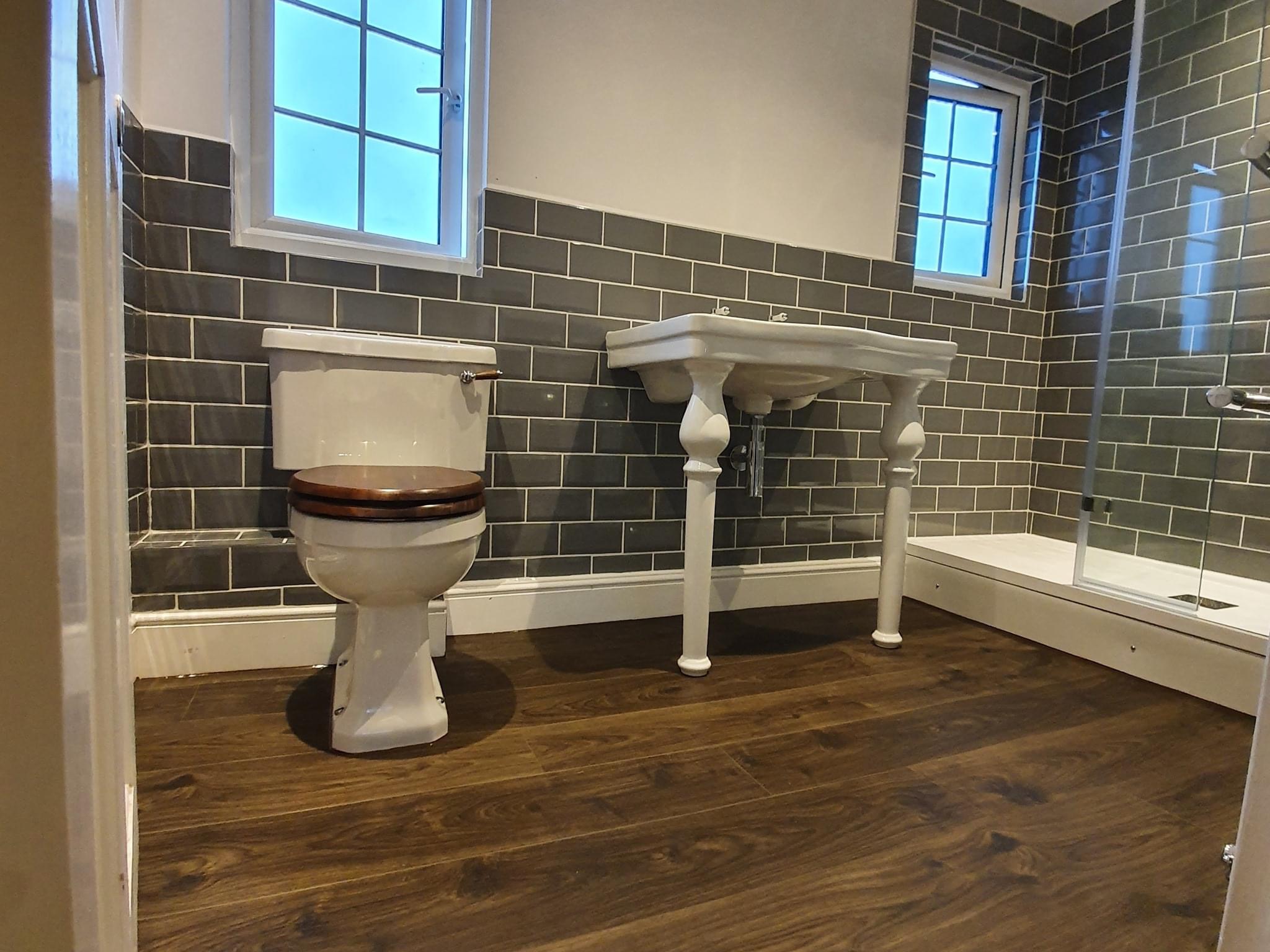 Traditional bathroom with a wooden toilet seat, pedestal console basin and grey metro tiles