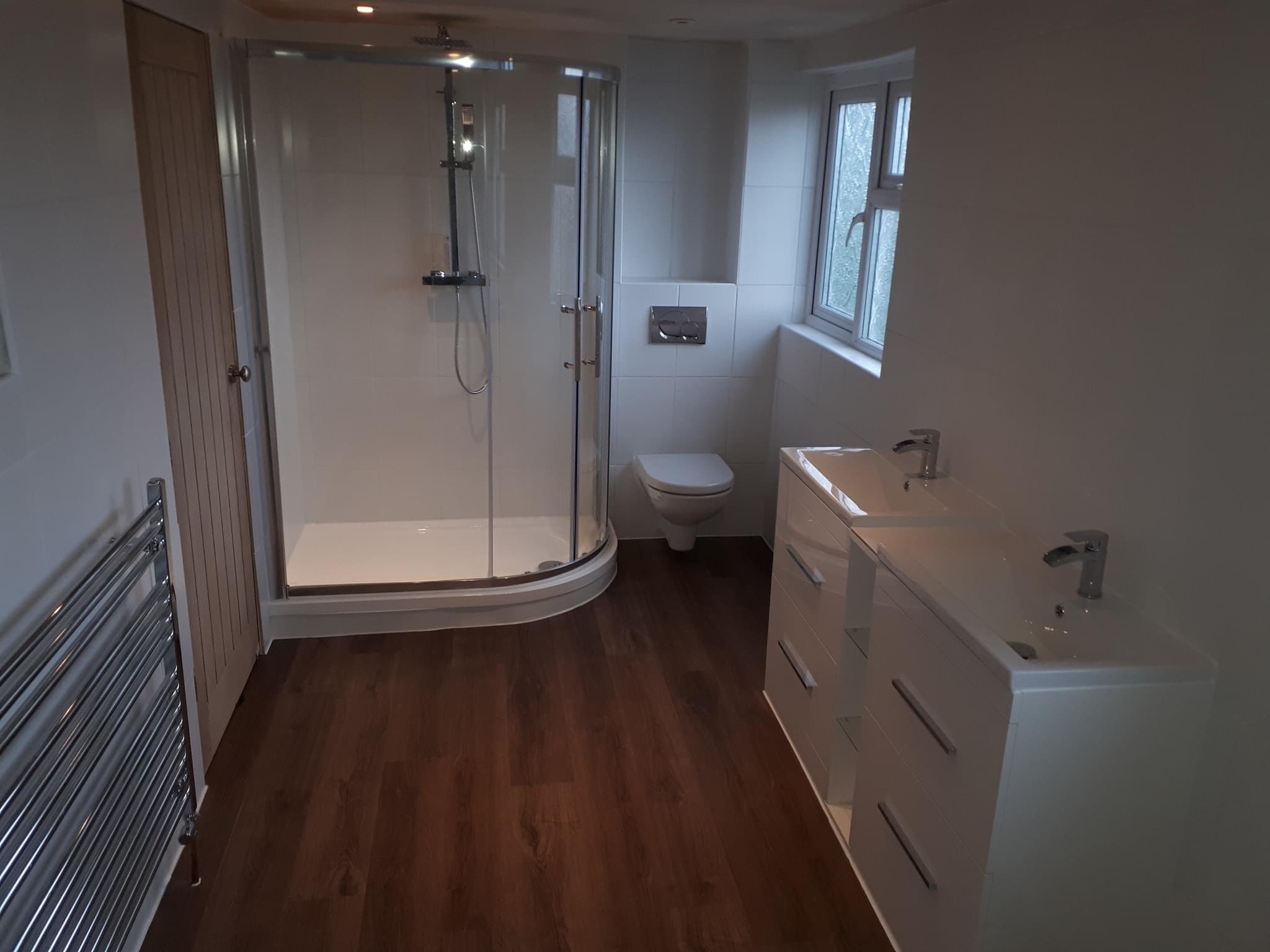 Finished bathroom with a quadrant shower, wall-hung toilet, double vanity and towel radiator