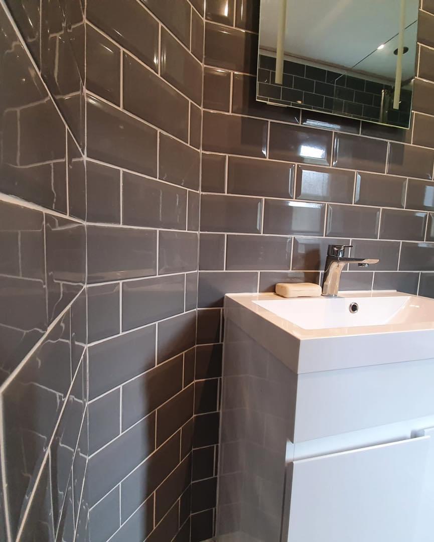 Grey gloss metro tiles around a white basin unit and mirror cabinet